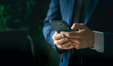 Biznesmen w garniturze piszący wiadomość na smartfonie – elastyczna oferta dla biznesu.